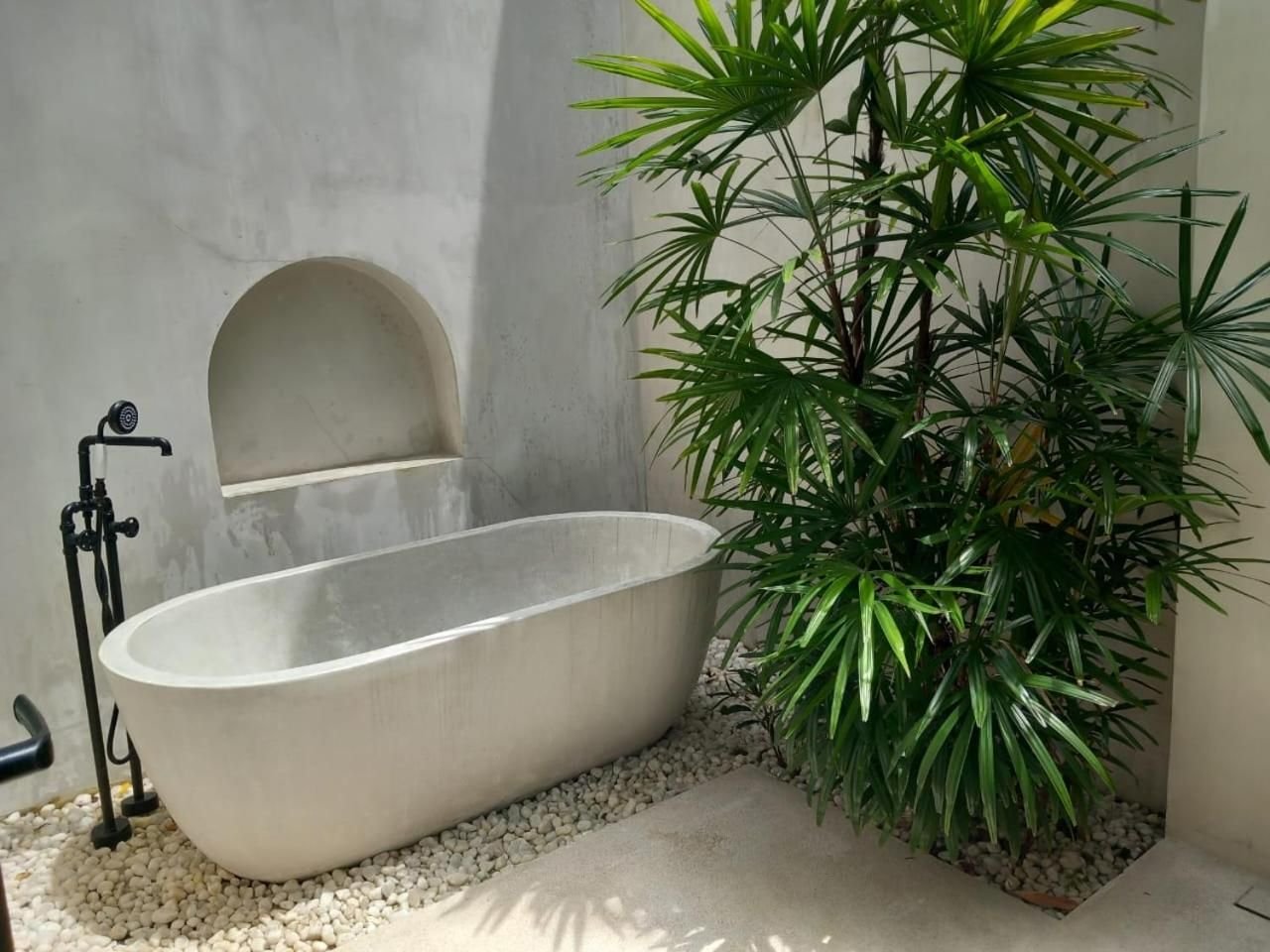 A freestanding terrazzo bath in a private planted courtyard
