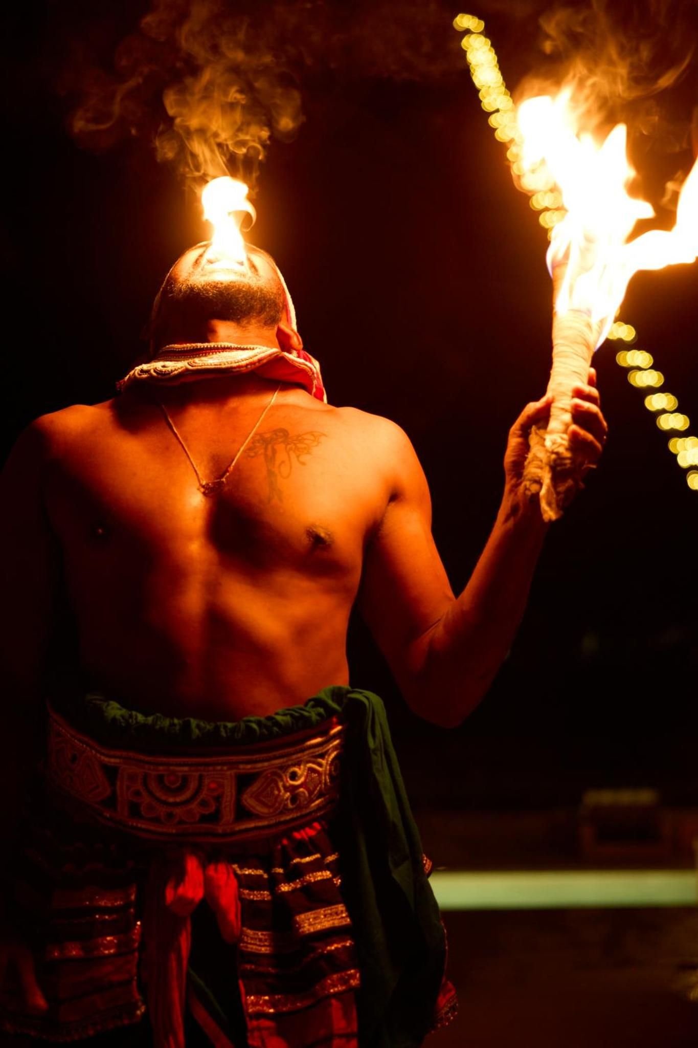 A dancer holding flaming torches at night