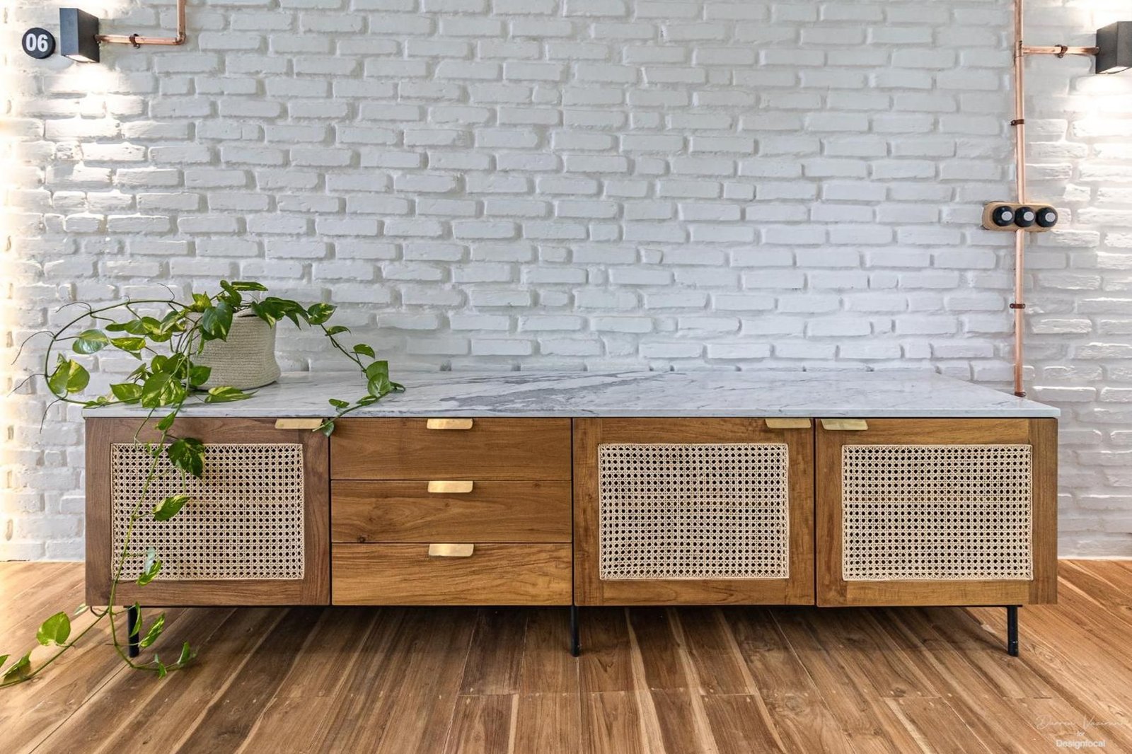 Teak and rattan sideboard against white brick