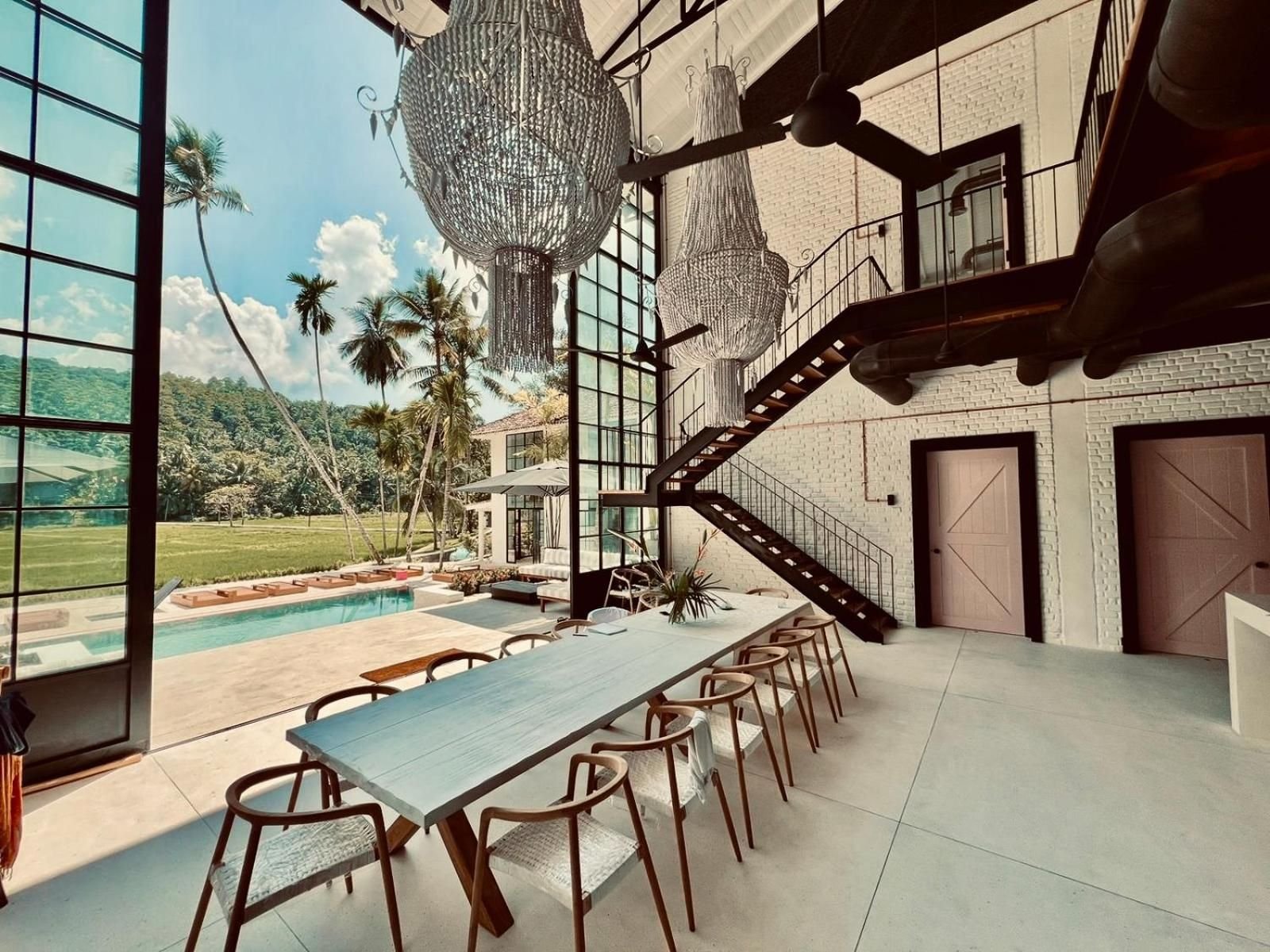 The double-height dining hall with its long communal table, open to the rice fields