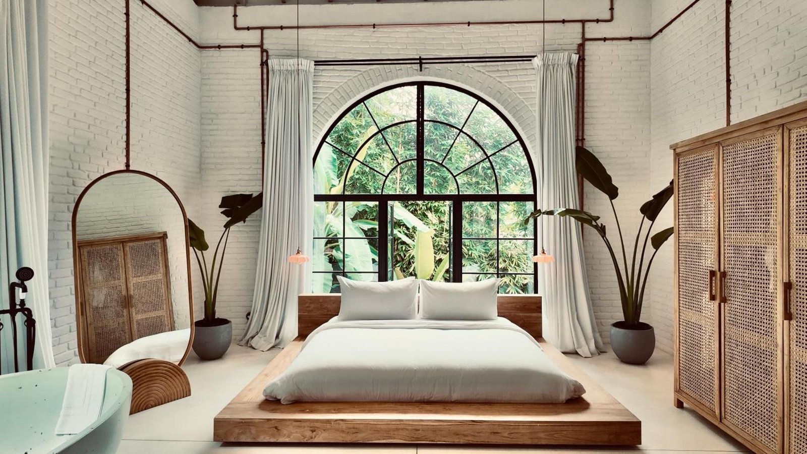 A king bed and terrazzo bath beneath arched steel windows at Miss Ceylon