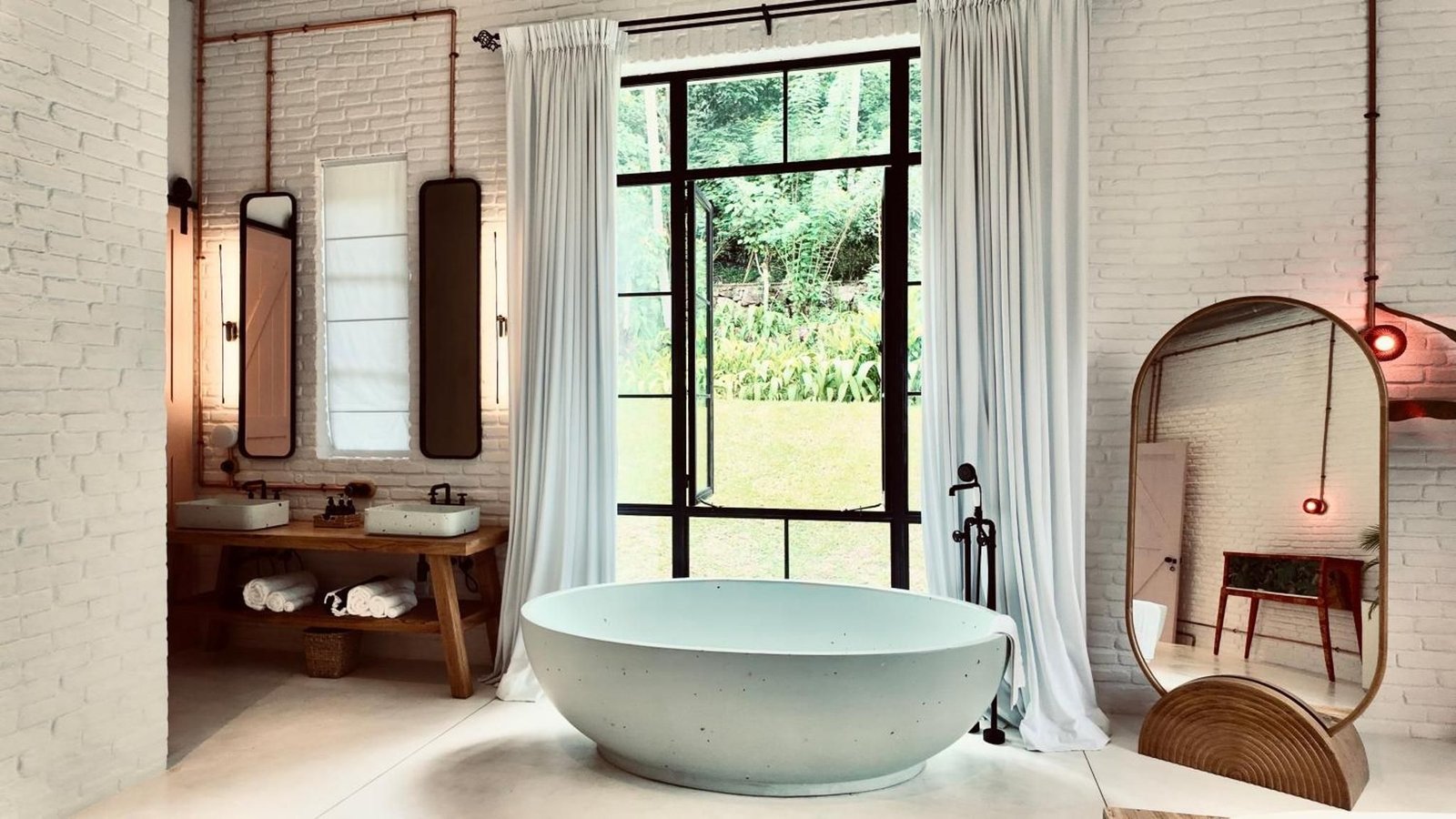 Freestanding terrazzo tub in front of a steel window