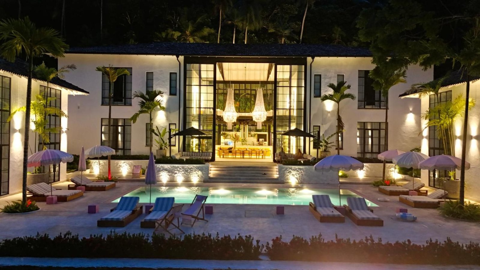 The hotel lit up at night across the pool