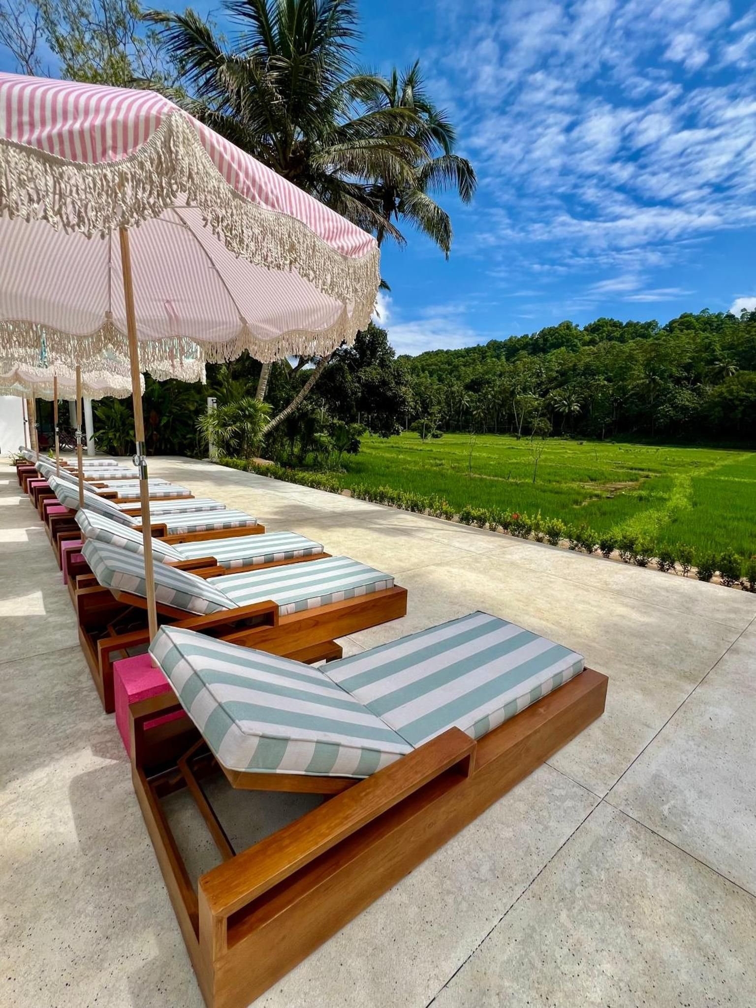 Striped loungers under pink umbrellas beside the pool